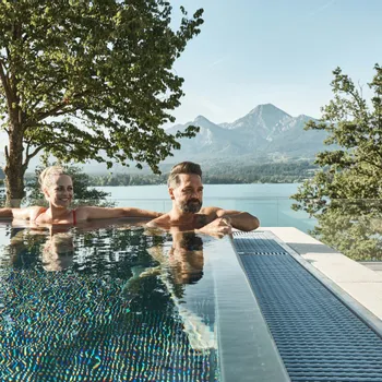 Water sports Couple relaxing in infinity pool with mountain and lake view in summer